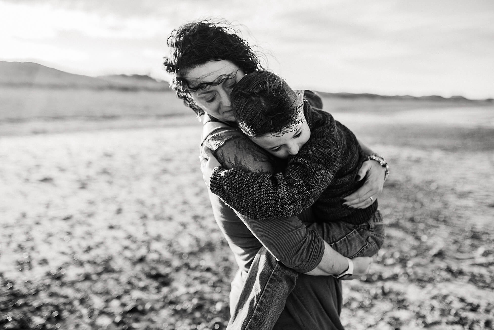 A black and white image of a mother holding her young son on the beach during their cape cod family photographer session