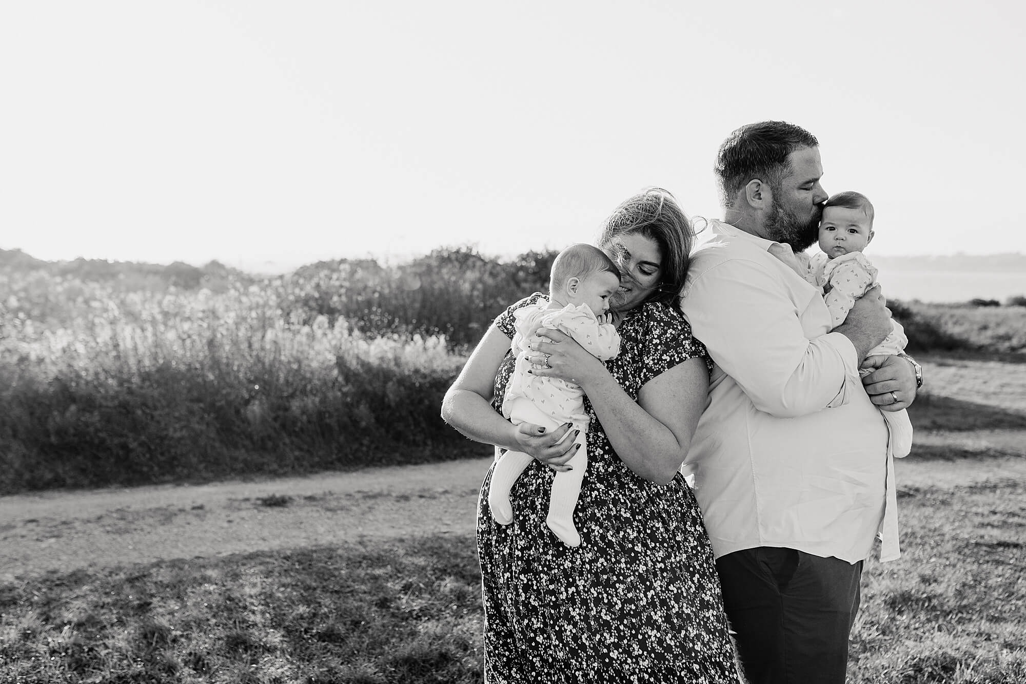 a black and white image of a family with two twin girls near the coast