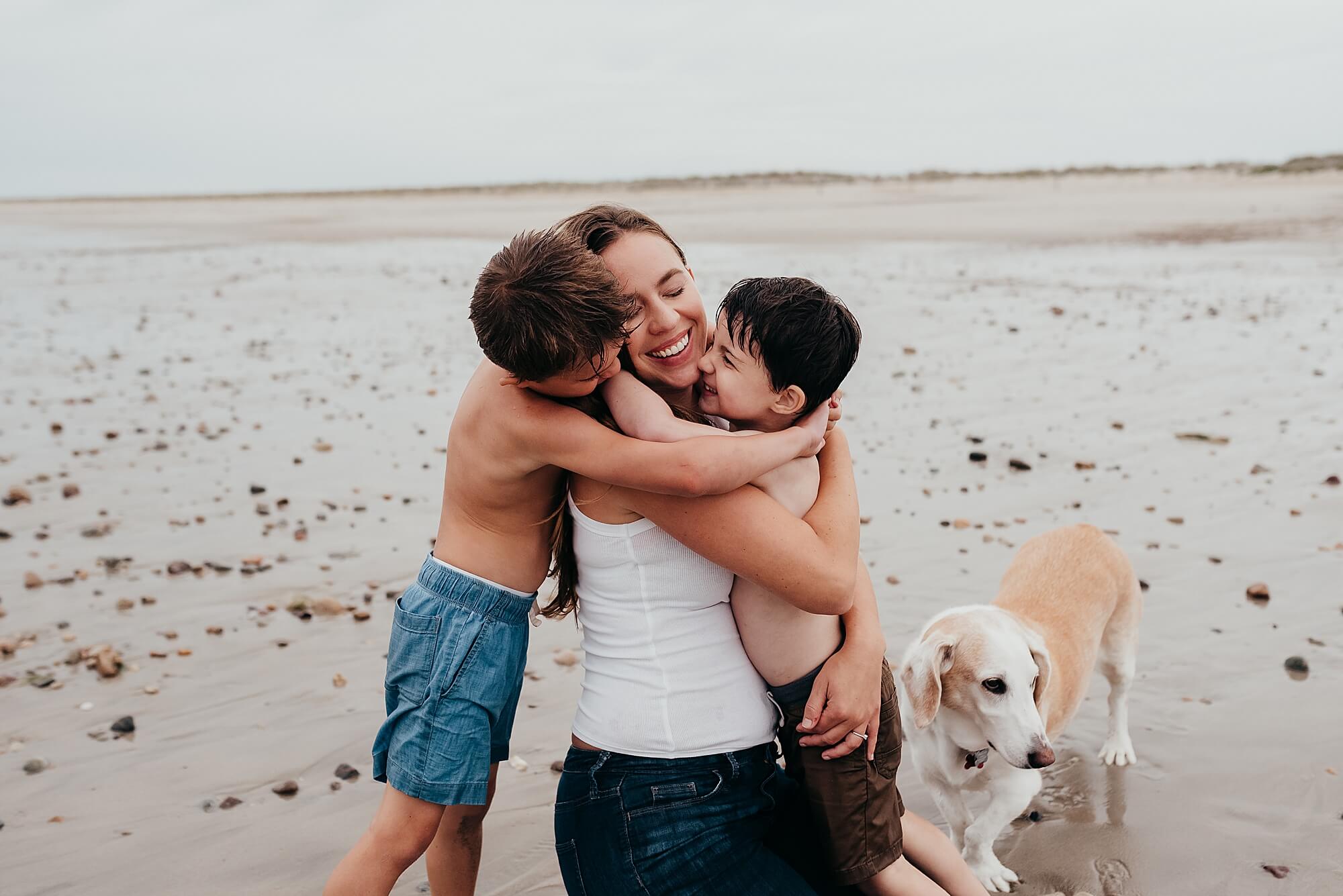 a mother is hugged by her two young boys on the beach during their stress free family pictures