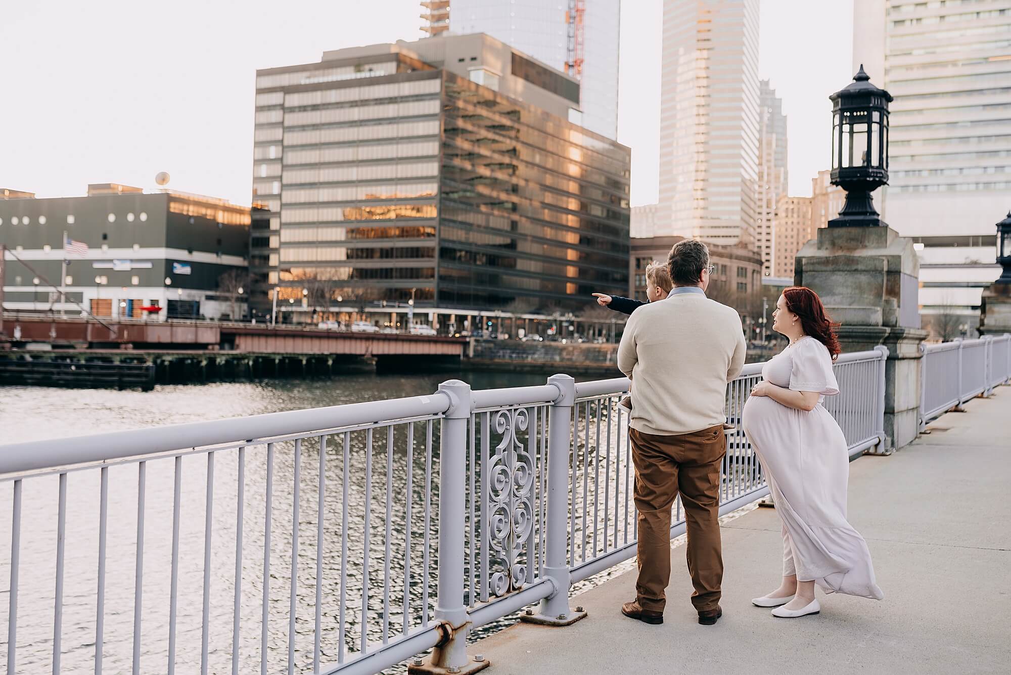 A young family stands on a bridge in the seaport Boston