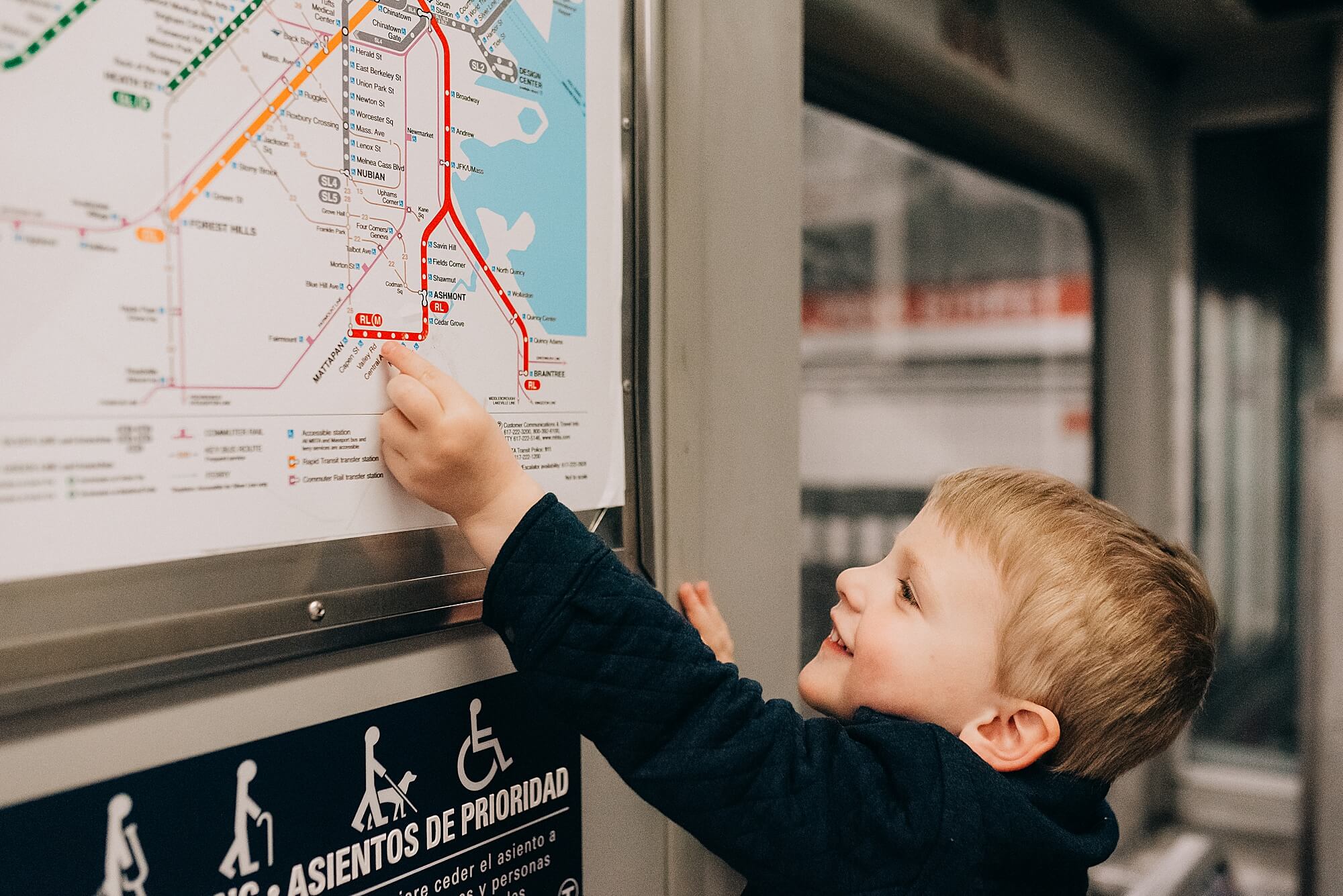 a young boy points to the map on a subway train in Boston