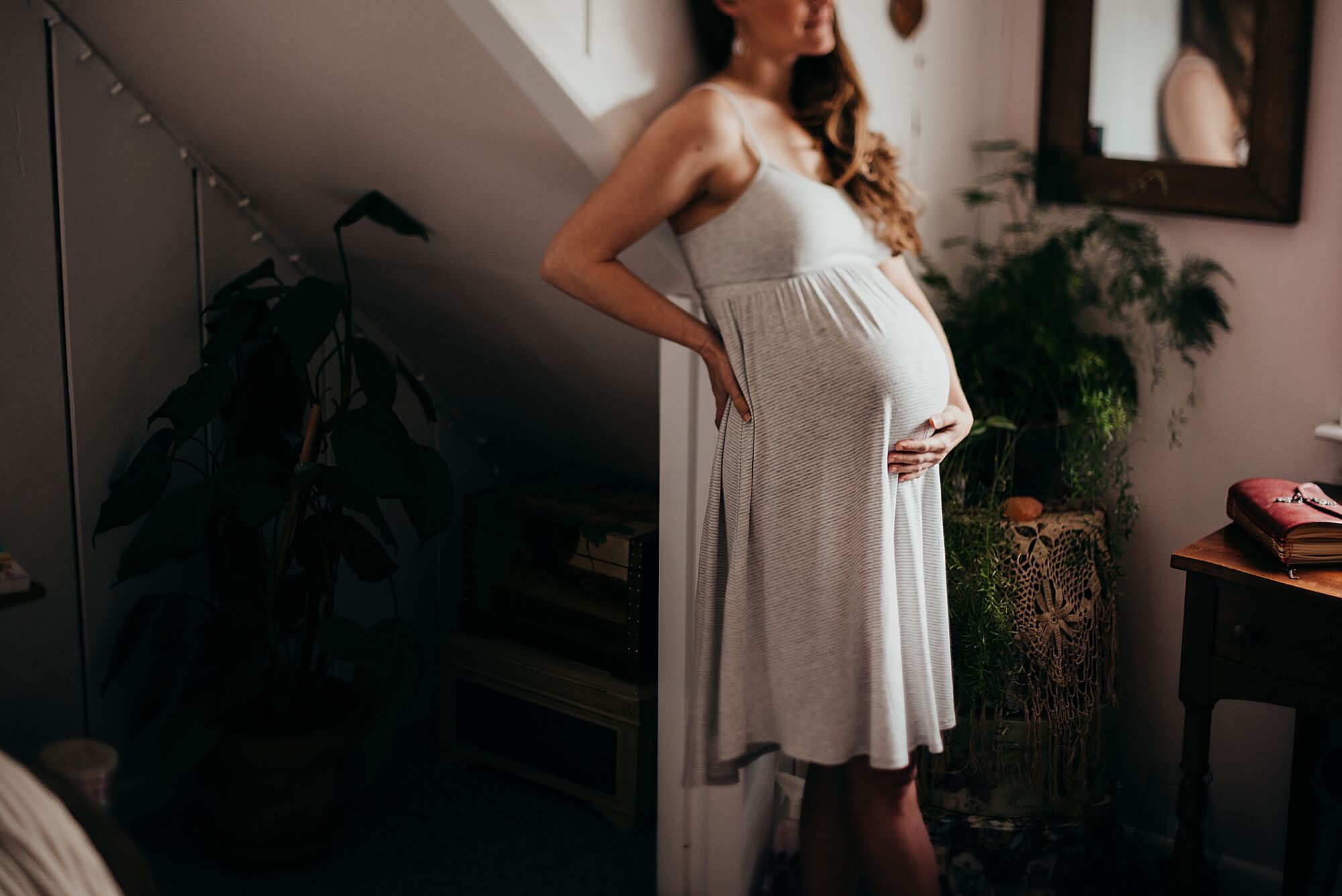 A pregnant mother stands in her bedroom