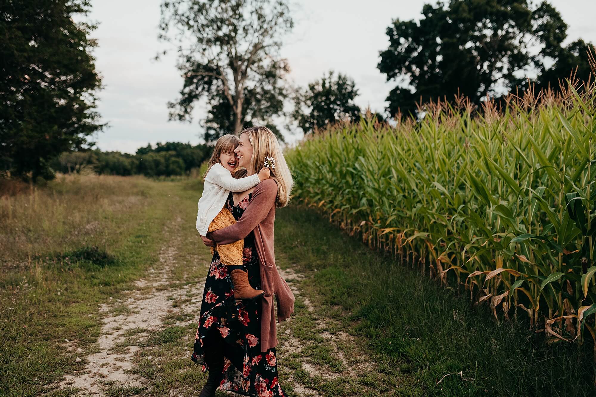 A mother dances with her daughter next to a corn field