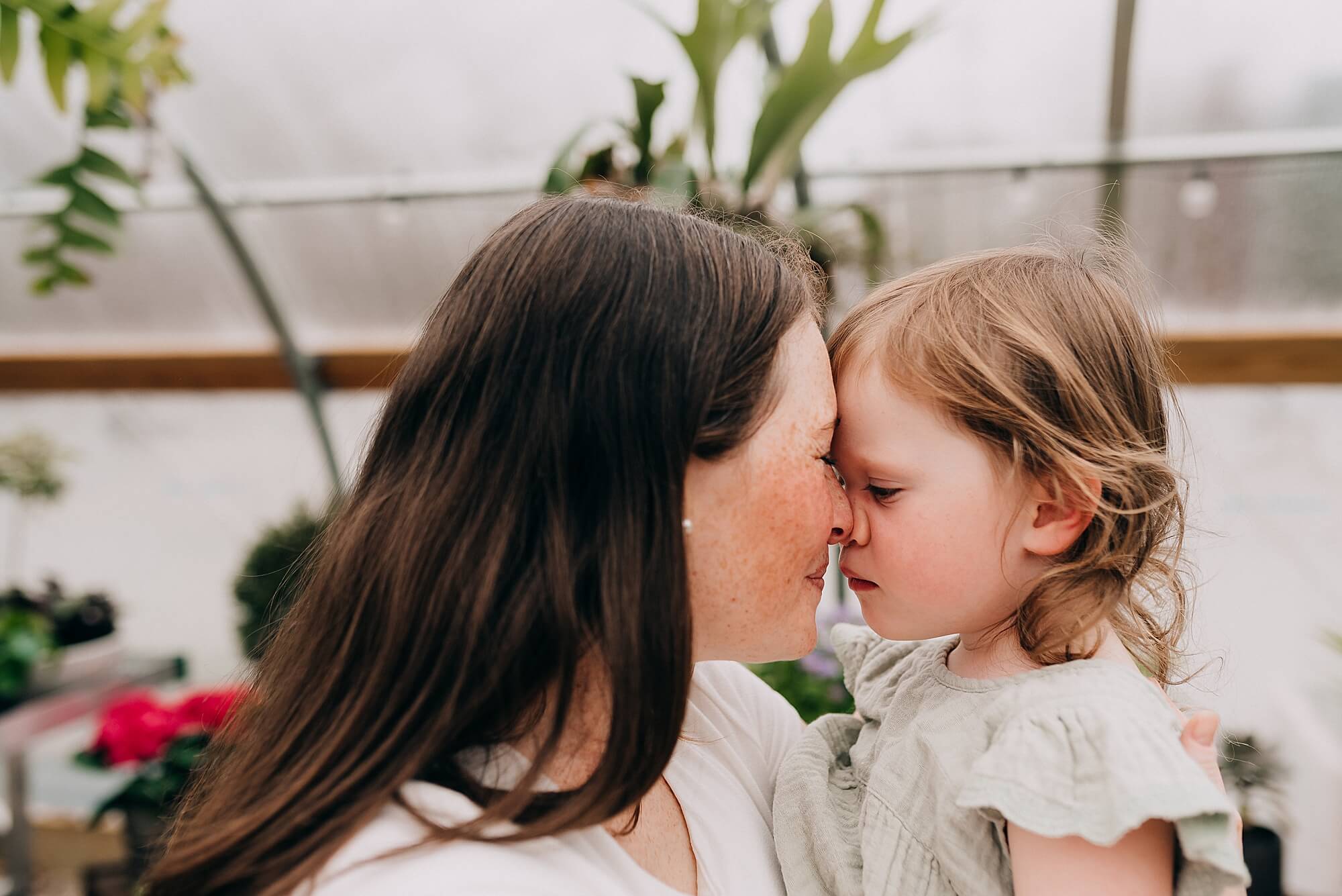 A mother and her young daughter press their noses together