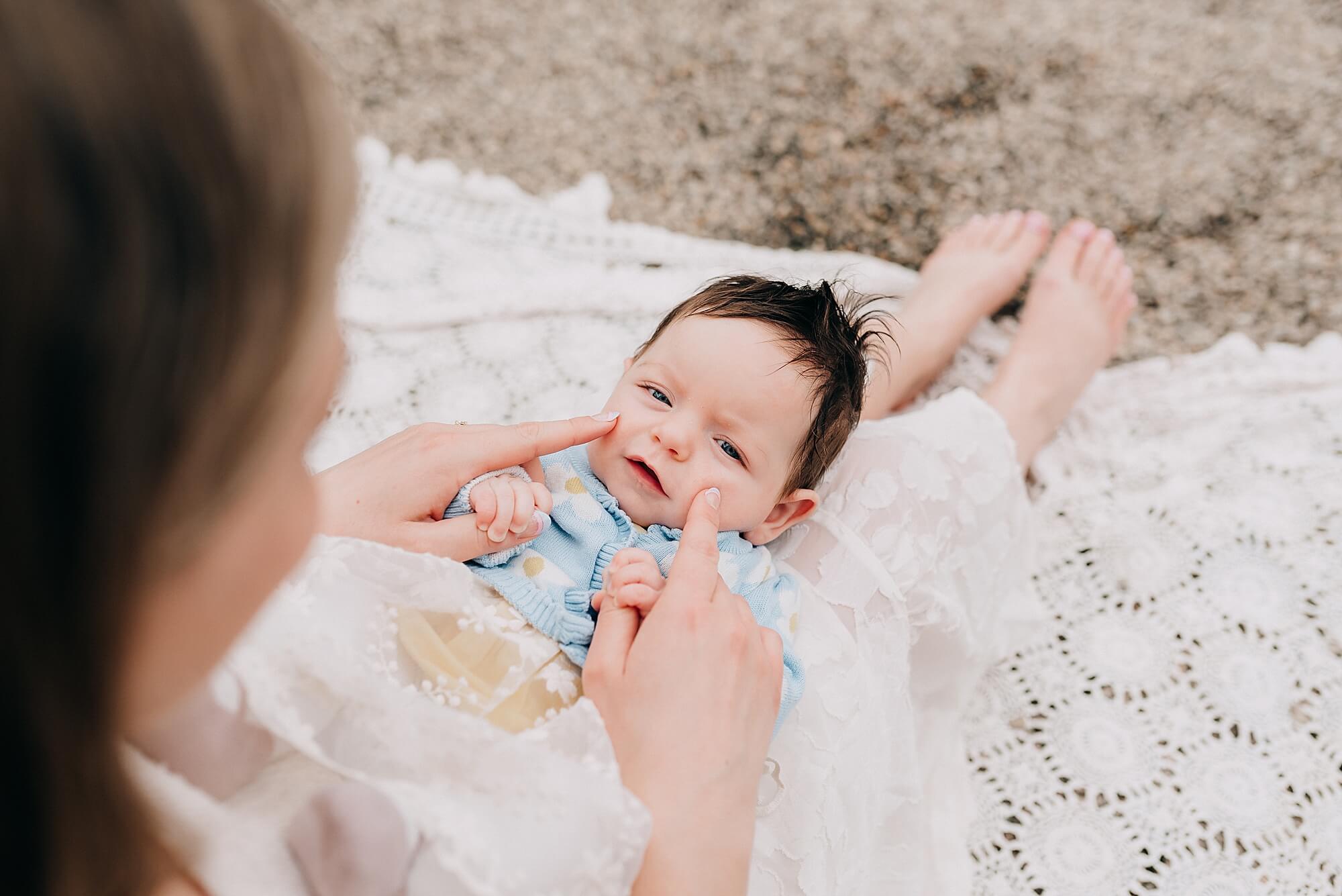 A mother lovingly touches her baby's cheeks as the baby looks at the camera