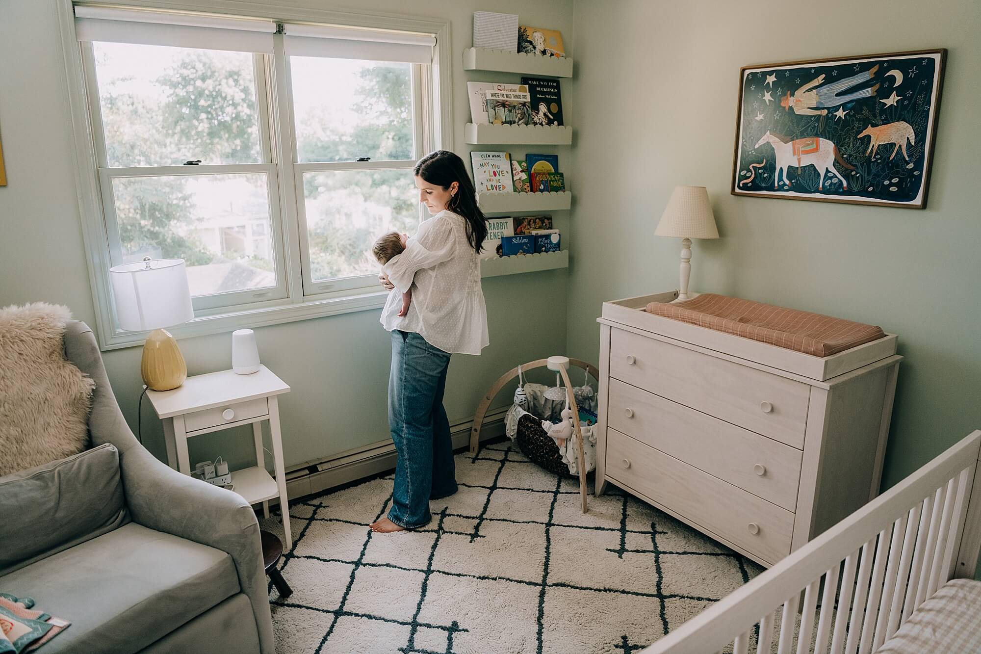 Mother snuggles her baby near the window during her Boston newborn photography session