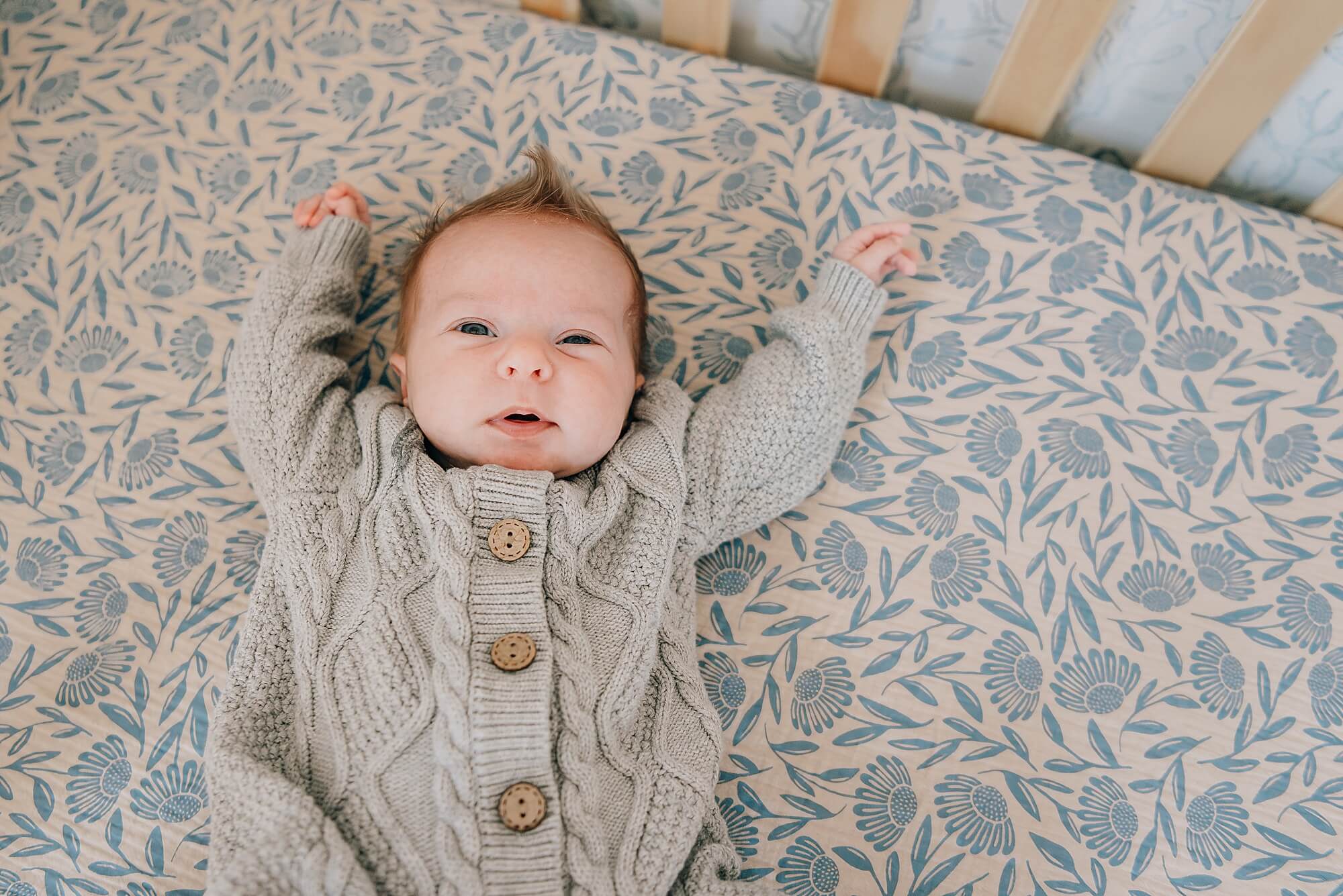 Newborn sleeping on bed in softly lit Boston nursery