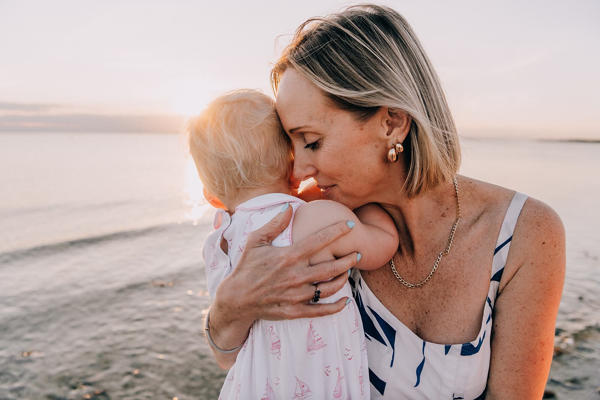 A mother and daughter snuggle at the beach in Falmouth Massachusetts