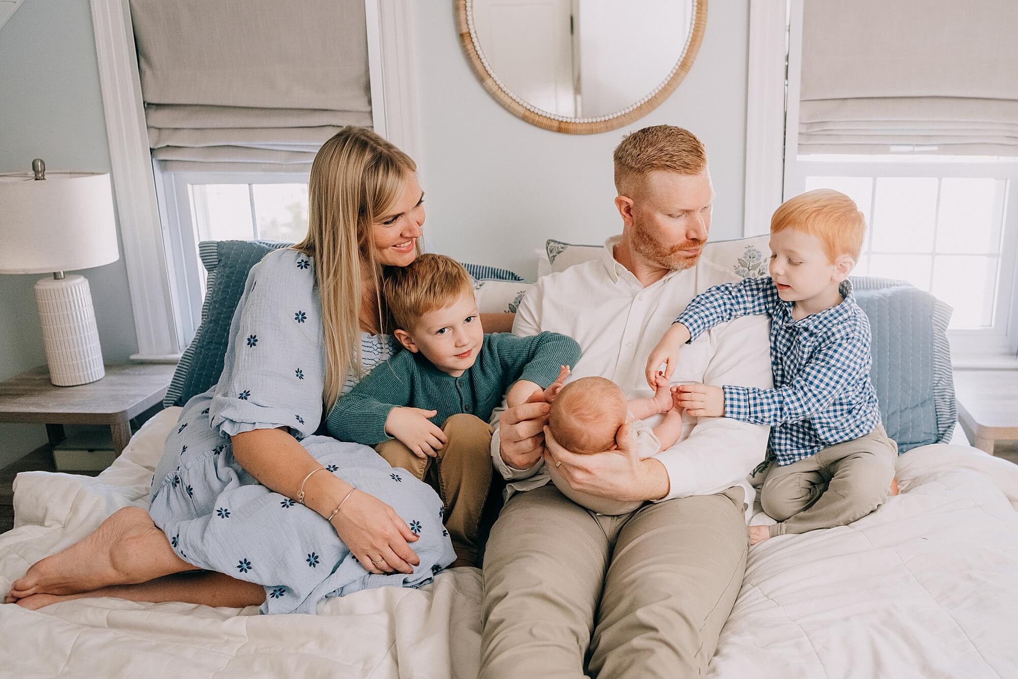 A family snuggle together on the bed during their photos with South Shore Newborn Photographer, Allison Wolf