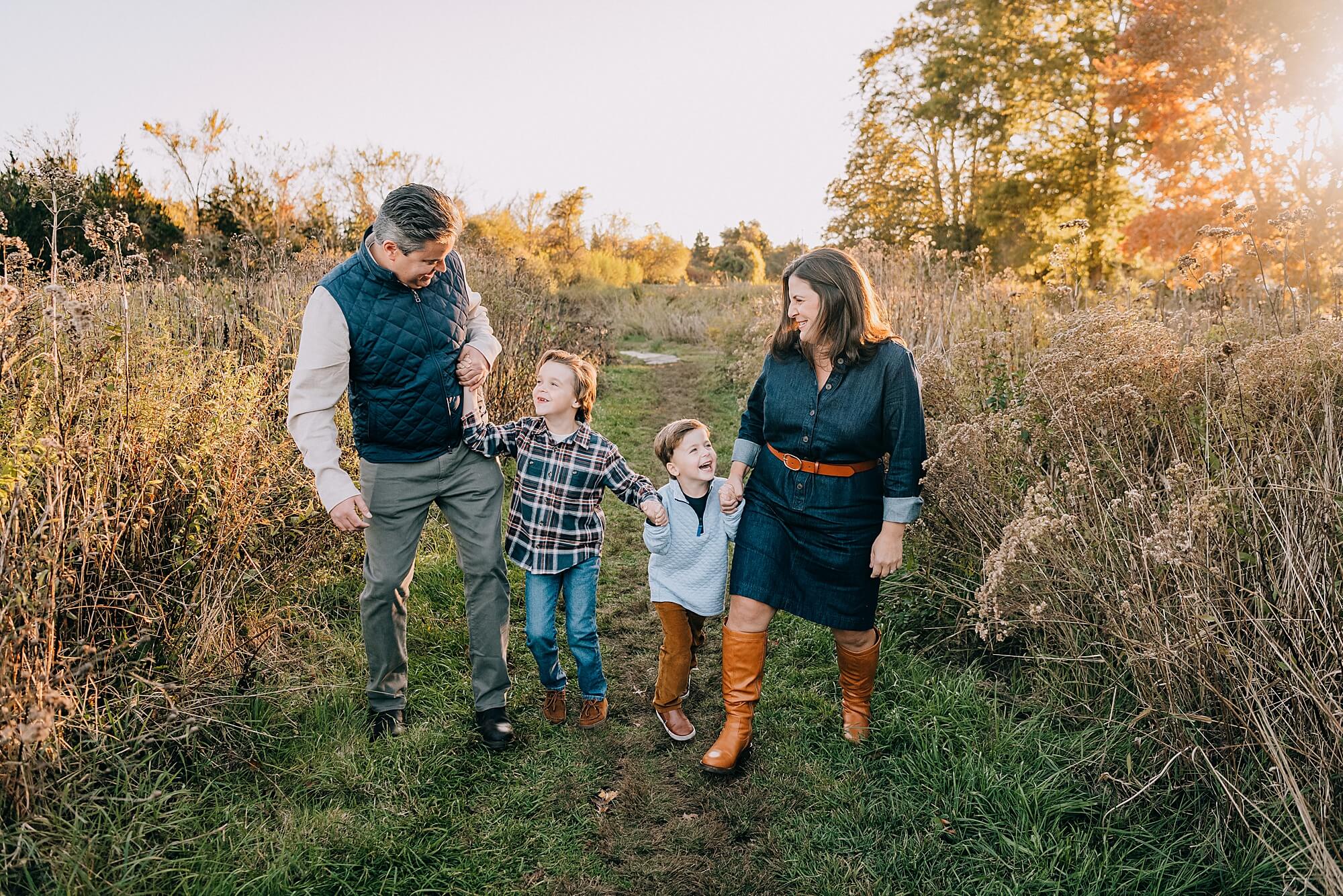 A family with two young boys have fun walking together through a field in Duxbury